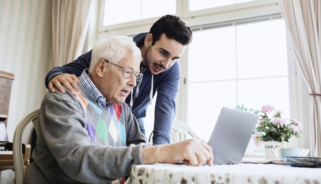 Caretaker and senior man using laptop in nursing home